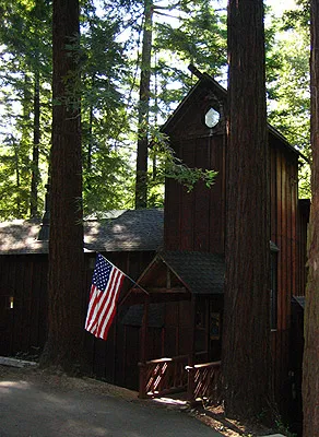 Wooden house among redwoods with an American flag hanging from the front porch